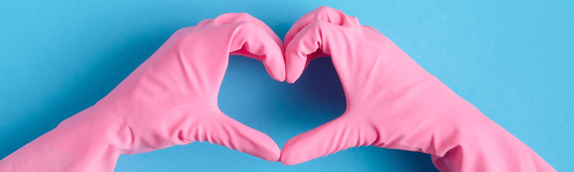 Hände in Reinigungshandschuhe, die ein Herz formen